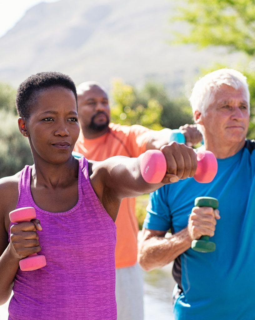 Black middle age woman, black middled age man, and older white man exercising outside.